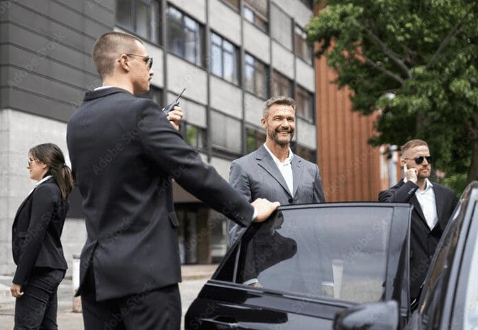 Two men in suits and ties standing next to a car.