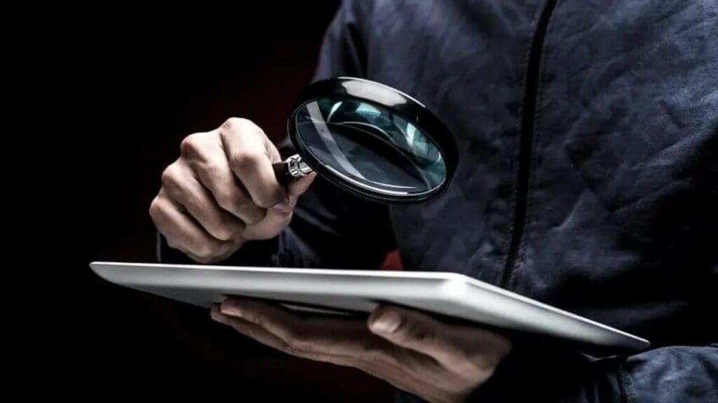 Person examining a tablet through a magnifying glass