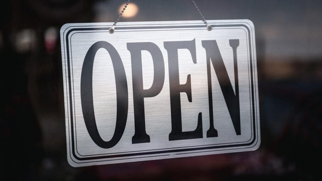 An open sign hanging on the glass door of a business
