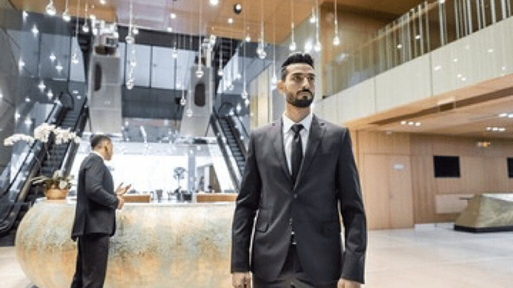 Security officer in a dark suit standing in a hotel lobby near the front desk