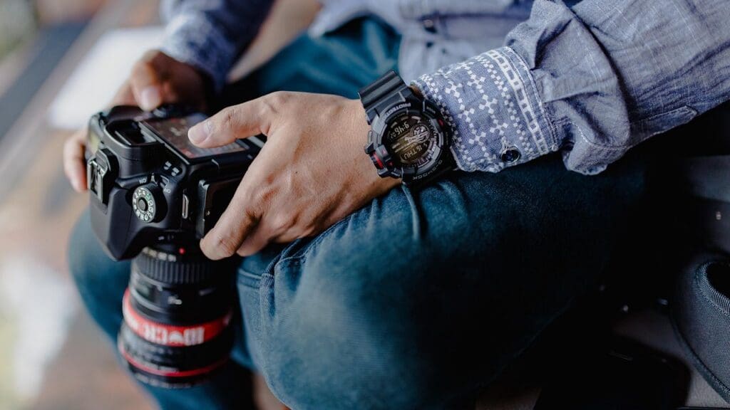 Hands holding a camera with a long lens, resting on a person's lap