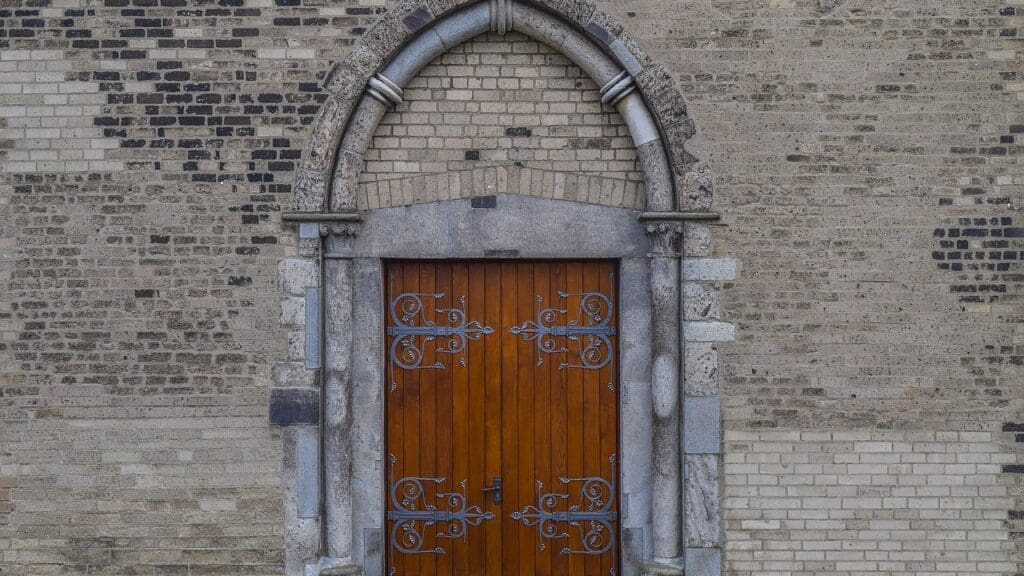 Arched wooden double door in the brick wall of a church