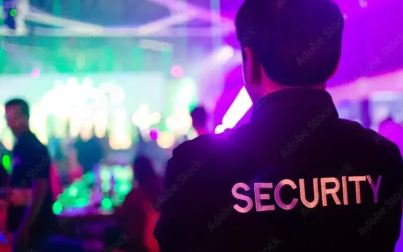 A man in black jacket with security on back. A man in black jacket with security on back.