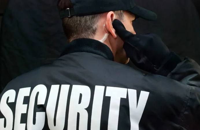 A security guard adjusts his ear plugs. A security guard adjusts his ear plugs.